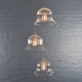 Bodium Large Ribbed Cluster Pendant Light with three clear ribbed glass shades hanging against a gray brick wall