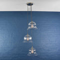 Bodium Large Ribbed Cluster Pendant Light with three clear ribbed glass shades hanging against blue brick wall