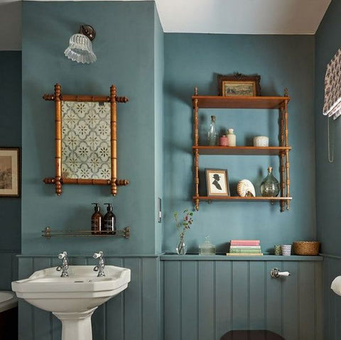 bodium ribbed bathroom light in a Bathroom with teal walls, white sink, wooden stool, and patterned floor.
