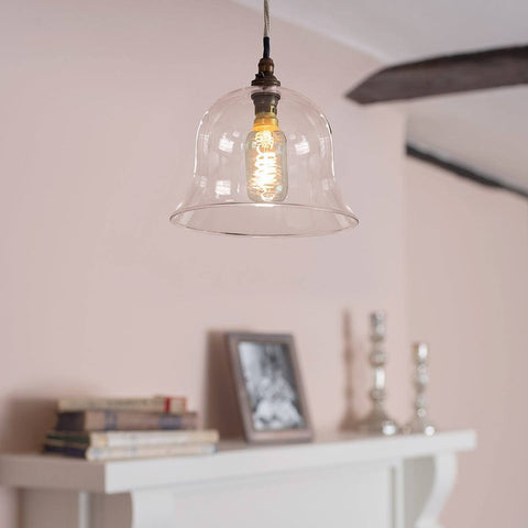 Pendant light with clear glass shade hanging above a fireplace.
