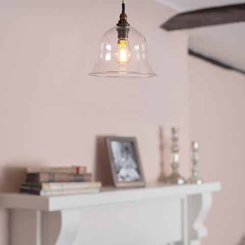 Pendant light with clear glass shade hanging above a fireplace.