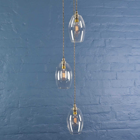 Camber small clear glass shade cluster pendant light with adjustable cords hanging against blue brick wall