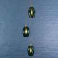 Camber small teal glass shade cluster pendant light with adjustable cords against blue brick wall