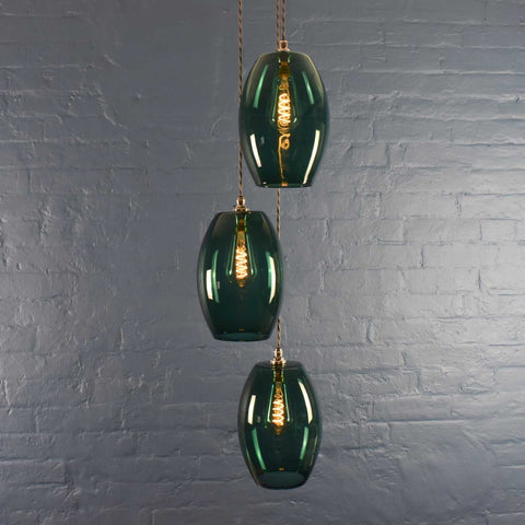 Camber Large Teal Glass Cluster Pendant Light with three handmade teal glass shades hanging against a gray brick wall