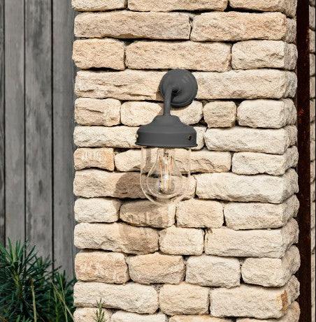 Outdoor barn wall light fixture on a stone wall with natural background