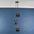 Hythe small smoked glass shade cluster pendant light with three hand-blown smoked glass cloche shades hanging against a blue brick wall