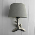 Laurier Wall Light with bronze leaf design and gray fabric shade mounted on white wooden wall