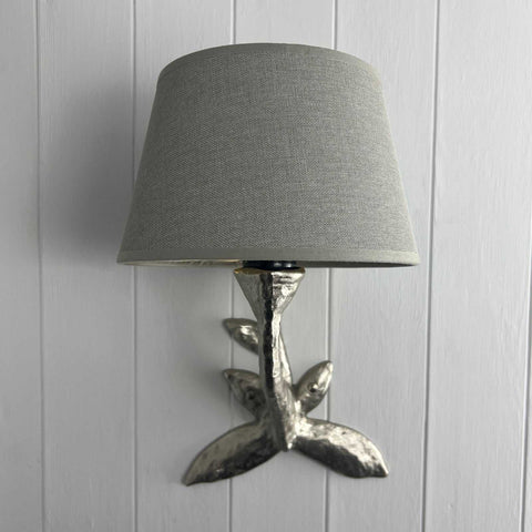 Laurier Wall Light with bronze leaf design and gray fabric shade mounted on white wooden wall
