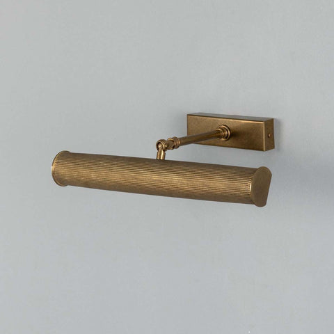 Cambridge Adjustable Brass Picture Light in reeded antique brass finish illuminating framed artwork on wall