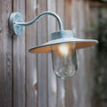 St Ives Swan Neck Light galvanized outdoor wall light with curved arm and glass shade mounted on wooden fence