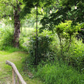 Steel festoon poles supporting outdoor string lights in a lush garden setting