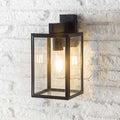 Belgrave Outdoor carriage light with off-black powder-coated steel frame and four glass panels mounted on white brick wall