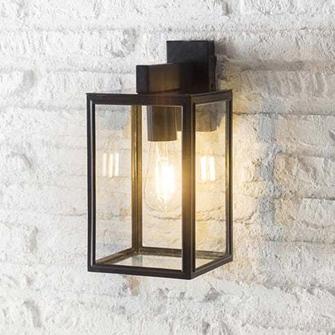 Belgrave Outdoor carriage light with off-black powder-coated steel frame and four glass panels mounted on white brick wall