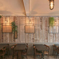 Denham Outdoor Swan Neck Wall Light with brass cage and glass shade illuminating rustic dining area