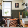 Ruben Small Outdoor Wall Light mounted in a stylish bathroom with a copper bathtub and dark green wainscoting