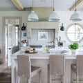 Modern kitchen interior with Fairburn IP23 wall lights mounted on white walls and pendant ceiling lamps above a large kitchen island with wicker bar stools
