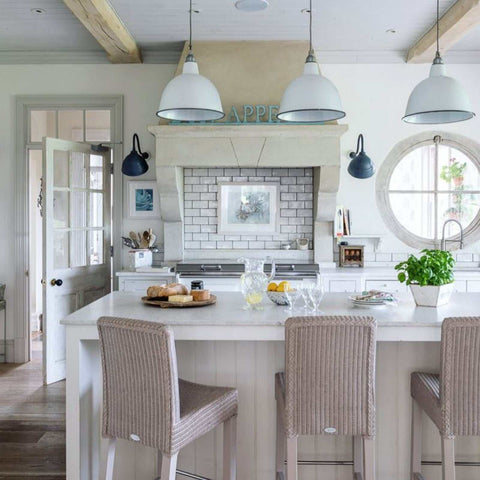 Modern kitchen interior with Fairburn IP23 wall lights mounted on white walls and pendant ceiling lamps above a large kitchen island with wicker bar stools