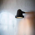 Thames Outdoor Spot Light in matte black mounted on wall with warm glow