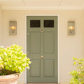 Pair of large Chiswick Outdoor Wall Lights with sleek glass design flanking a green front door in an elegant outdoor setting