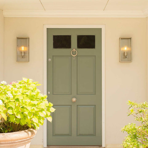 Pair of large Chiswick Outdoor Wall Lights with sleek glass design flanking a green front door in an elegant outdoor setting