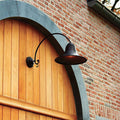 Extra large Kew Outdoor Wall Light in bronze finish mounted on brick wall above wooden arched door