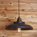 Telal Pendant Light with vintage braided cord and industrial metal shade hanging against wooden wall