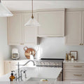 Rebell Prismatic Glass Pendant Light hanging in a modern kitchen with white cabinetry and stainless steel appliances