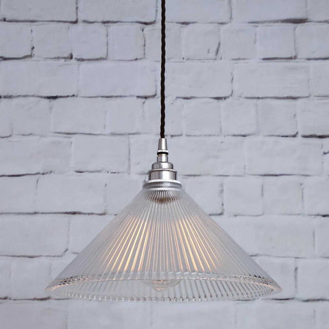 Rebell Prismatic Glass Pendant Light with a conical prismatic glass shade hanging against a white brick wall background