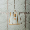 Medium Luxor Lantern Pendant Light with clear glass panels and antiqued brass frame hanging against textured wall