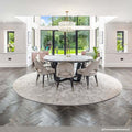 Artemis Chandelier pendant light with brass finish and glass rods hanging above round dining table in modern dining room