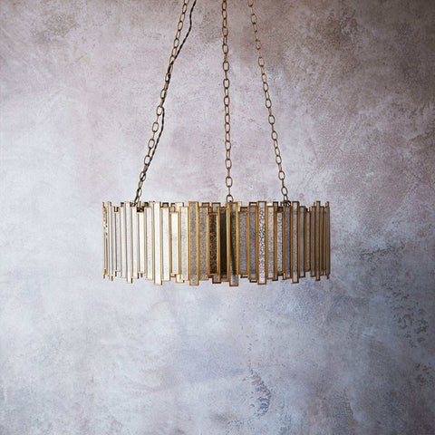 Pooky Melvillous chandelier pendant light with mercerised glass and gold geometric frame, suspended by chains against textured wall