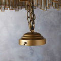 Close-up of the gold ceiling mount and chain of the Pooky Melvillous Chandelier Pendant Light with a blurred architectural background.