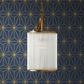 Pooky Valli Pendant Light with brass finish and glass rod lantern design hanging against geometric patterned wall
