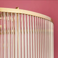 Close-up of Pooky Athena Chandelier pendant light with brass frame and glass rods against pink background