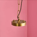 Pooky Athena Chandelier pendant light with brass frame and twisted cord against pink background