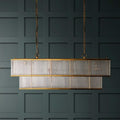 Odin Chandelier pendant light with double-tiered brass frame and handcrafted glass rods hanging against dark paneled wall