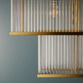 Close-up of Odin Chandelier showcasing handcrafted glass rods and golden brass frame details