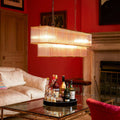 Modern Odin Chandelier pendant light with glass rods and brass frame above a stylish living room table.