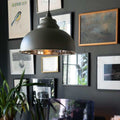 Brampton Grey Pendant Light with domed shape and polished nickel interior hanging above a desk in a modern living space with framed artwork and plants.