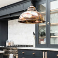 Brampton burnished pendant light with hand-burnished brass finish and hammered interior hanging in modern kitchen