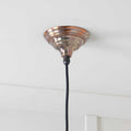 Brampton burnished pendant light with hand-burnished brass metal finish and black cord hanging from ceiling
