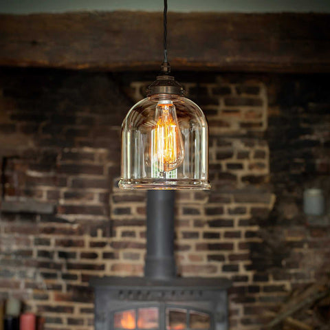 Hythe clear hand-blown glass pendant light with vintage bulb hanging in rustic room