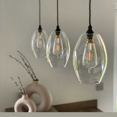 Three Camber Medium Clear Glass Shade pendant lights hanging in a modern interior with neutral decor.