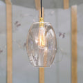 Camber large clear glass shade pendant light with exposed filament bulb and brass fitting hanging in modern interior