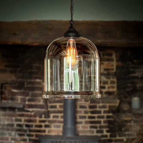 Hythe large clear glass shade pendant light with exposed filament bulb and black fixture against rustic brick wall background