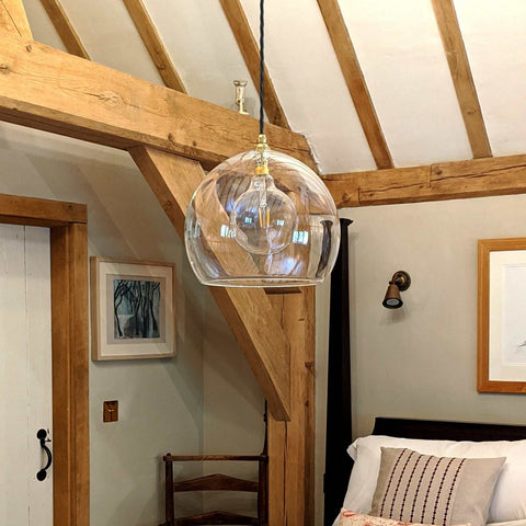 Soho Extra Large clear glass pendant light with adjustable cord hanging in rustic bedroom