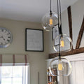 Soho large clear glass shade cluster pendant light with three hand-blown glass globes and adjustable cords in a modern living room setting