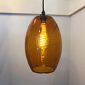 Camber large amber glass shade pendant light with warm glowing filament bulb hanging indoors