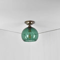 Soho small teal glass shade flush ceiling light with a round teal blue glass diffuser and antique brass fitting mounted on a white ceiling in a modern room