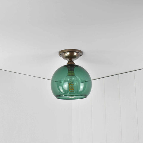 Soho small teal glass shade flush ceiling light with a round teal blue glass diffuser and antique brass fitting mounted on a white ceiling in a modern room